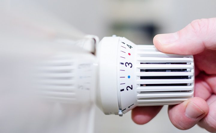 Close Up Of Hand Adjusting Heating Thermostat.